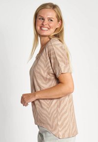 Beiges T-Shirt mit einem dezenten Zebramuster, rundem Halsausschnitt, kurzen Ärmeln und einem etwas längeren Saum auf der Rückseite. Weiche Stoffstruktur.