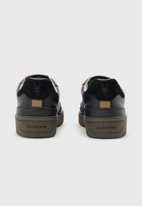 Sneaker in pelle nera con un accento in suede nero testurizzato sulla parte posteriore. Presenta una suola in gomma e il marchio "ALLSAINTS" sul retro.