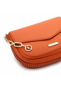 Bolso de mano de cuero naranja con un acabado texturizado, que presenta una cadena dorada y herrajes, así como costuras puntiagudas a lo largo de los bordes.