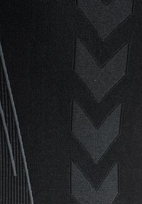 Svarta träningsleggings med en texturerad tyg, utrustat med vertikala ränder och diagonala chevron-mönster i en något mörkare nyans.