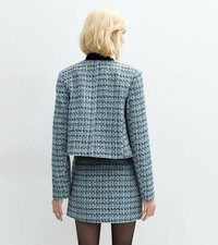 Giacca in tweed texturizzato di colore blu chiaro e nero, dal design cropped, con maniche lunghe e taglio dritto, abbinata a una gonna aderente coordinata.