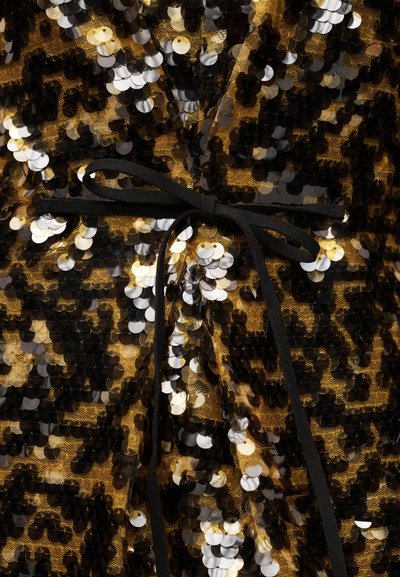 Black decorative bow tied over shiny gold, black, and silver sequin fabric with leopard print pattern.