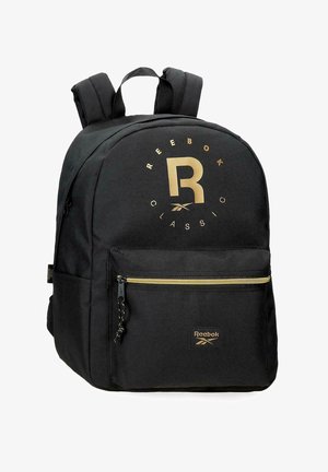 Mochila Reebok Classic negra con logo dorado, bolsillo frontal con cremallera, correas acolchadas para los hombros y asa superior de transporte.