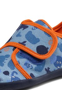 Blauer Stoffschuh mit orangefarbener Borte, der ein spielerisches Muster von Tieren zeigt. Klettverschluss für einfache Anpassung. Weiches Sohlen-Design.
