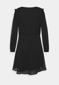 Schwarzes Kleid mit langen, durchsichtigen Ärmeln, strukturiertem Polka-Dot-Muster, tailliertem Oberteil und ausgestelltem Rock. Der Saum ist hinten etwas länger.