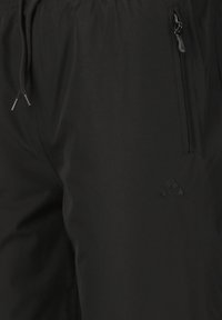 Shorts noirs en tissu léger avec une taille élastique, dotés d'une poche zippée et d'un petit logo sur le devant.
