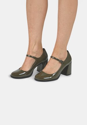 Green patent leather Mary Jane heels with a round toe, adjustable strap, and chunky block heel. Smooth texture with a glossy finish.