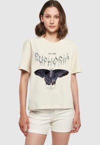 Cremefarvet bomulds t-shirt med et stort sort møl grafik og sølvtekst, korte ærmer og en afslappet pasform.