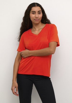 Red short-sleeve V-neck t-shirt, made of smooth fabric, featuring a relaxed fit and clean design, paired with black pants.