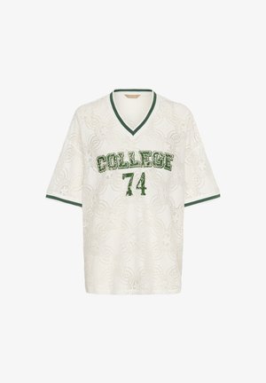 Balts mežģīņu T-krekli ar V-veida kaklu, kas rotāti ar zaļu drukātu grafiku "KOLEĢIS" un "74". Īsas piedurknes ar zaļiem akcentiem.