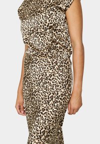 Ensemble à imprimé léopard en tissu lisse ; design ajusté avec des manches courtes, présentant un mélange de couleurs beige, brun et noir.