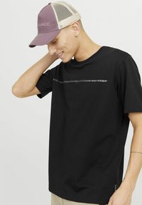Sort bomulds tshirt med korte ærmer, der har et vandret grafik- og logo-detail på brystet. Glat tekstur og afslappet pasform.