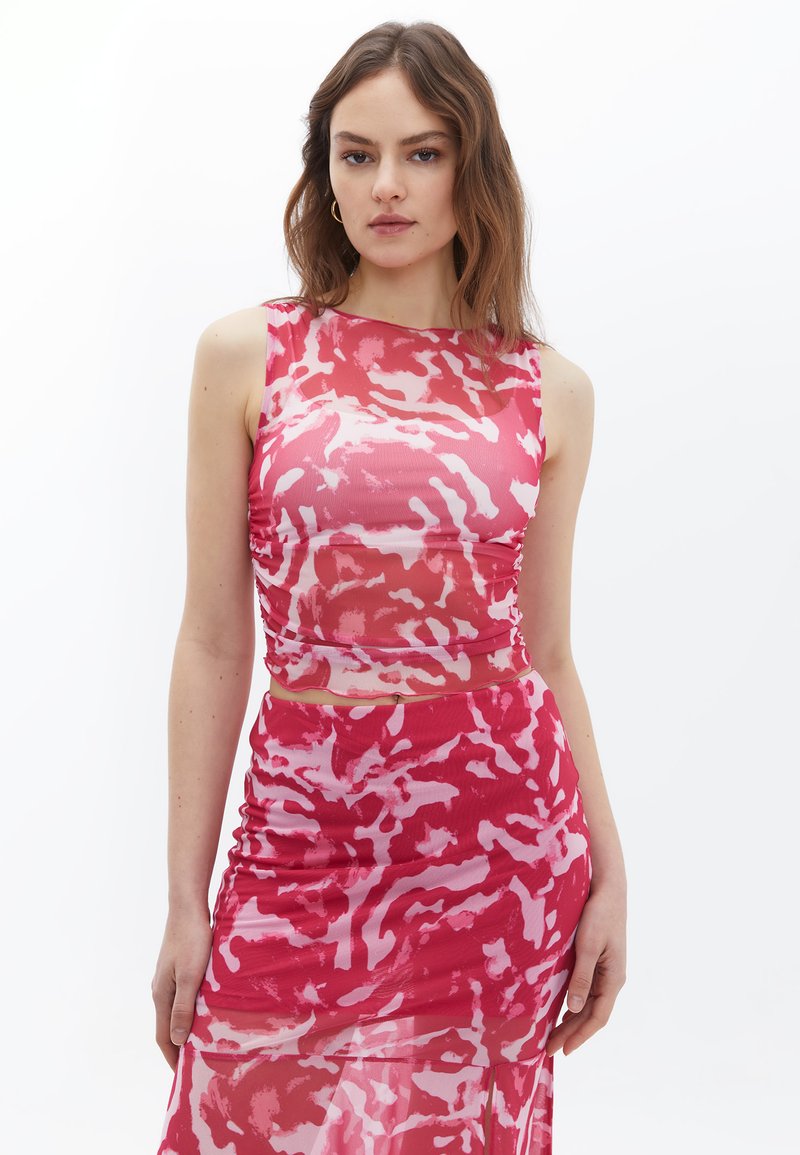 Roze en rode gebloemde crop top met een aansluitend ontwerp en een mouwloze snit, gecombineerd met een bijpassende gerimpelde rok, gemaakt van een lichtgewicht stof.