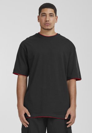 T-shirt noir à manches courtes avec des détails en accent rouge au col et aux manches. Fabriqué en coton, il présente une coupe décontractée et un ourlet droit.