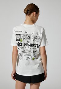 Biała bawełniana koszulka z nadrukiem na plecach, zawierająca czarne i zielone wzory, w tym postacie i symbole z serii "Rick and Morty".