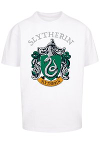 Hvit t-skjorte med et sentralt Slytherin-våpen i grønt med en sølvslange, detaljert med dekorative elementer og et gult banner som sier "Slytherin."