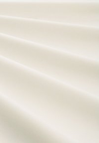 Tejido blanco suave y cremoso con pliegues suaves y uniformes que crean sombras sutiles y una textura sedosa.