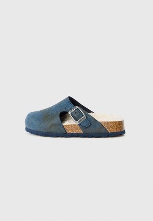 Sinine sametist puuneline, millel on pahklu- ja hõbedane pannal. Omab korkpaari, millel on tekstuuriga pind ja pehme sisemine vooder.