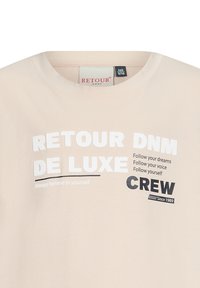 Beige katoenen t-shirt met een ronde hals, voorzien van grote witte en zwarte tekst. De tekst bevat het merk en motiverende zinnen.