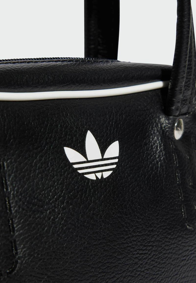 Schwarze Lederhandtasche mit weißen Akzentpaspeln. Verfügt über das ikonische weiße Dreiblatt-Logo und Reißverschlussdetails. Strukturierte Oberfläche mit Steppnähten.