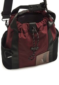 Borsa a sacco in tessuto rosso con dettagli neri, spallacci regolabili e tasca laterale in rete. Presenta un'etichetta con logo e chiusura superiore a coulisse.