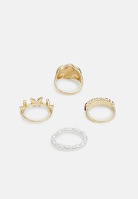 Conjunto de quatro anéis: três de ouro com vários designs (borboleta, texturizado, com accentuação de rubi), além de um anel com contas de pérola branca.