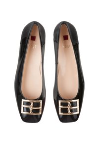Le ballerine in vernice nera presentano una punta quadrata, un accento in metallo dorato nella parte anteriore e una fodera interna liscia beige.