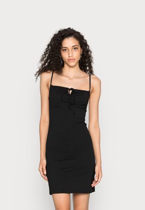 Vestido preto justo com alças finas, corpete franzido e detalhe de laço na parte da frente. Tecido liso e elástico com um design simples e elegante.
