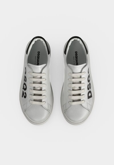 Paire de baskets en cuir blanc avec lacets blancs et texte noir "DSQUARED2" sur les côtés, avec des accents noirs au talon.