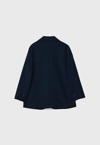 Chaqueta azul marino de tejido suave, con cuello, mangas largas y un ajuste ligeramente holgado con puños abotonados.