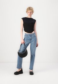 Črn skrajšan top s strukturiranim dizajnom, svetlo modri visokotlačni jeans, črna torba z zakovicami in robustni črni platform čevlji.
