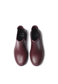 Bottes en caoutchouc bordeaux au design épuré, avec des panneaux latéraux élastiques et des semelles intérieures texturées. Surface lisse avec des orteils arrondis et des talons bas.
