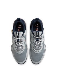 Scarpe da ginnastica grigie con tomaia in rete, accenti blu navy a contrasto e intricati motivi testurizzati. I lacci e le suole imbottite completano il design.
