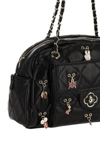 Bolso negro acolchado de cuero con herrajes plateados. Cuenta con un bolsillo frontal y varios encantos decorativos attached. La correa tiene un diseño de cadena.