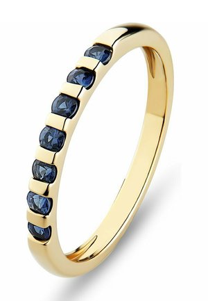 Goldring mit einer glatten, polierten Oberfläche, der sieben dunkelblauen Edelsteine zeigt, die in einem versetzten Muster entlang einer Seite gesetzt sind.