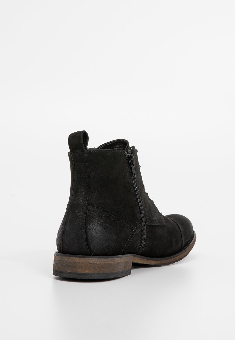 Schwarze Lederknöchelstiefel mit seitlichem Reißverschluss, runder Zehe und strukturierter Oberfläche. Verfügt über einen niedrigen, gestapelten Absatz und subtile Nähdetails.