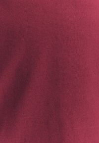 Burgundy kangas kuris turi lygų, šiek tiek tekstūrinį paviršių su vienodu spalvos pasiskirstymu. Nėra matomų raštų ar aparatūros detalių.