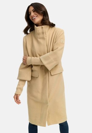 Beige, oversized wollen jas met een hoge kraag, brede mouwen en twee voorzakken. Kenmerkt zich door een gestructureerde stof en subtiele branding op de mouw.