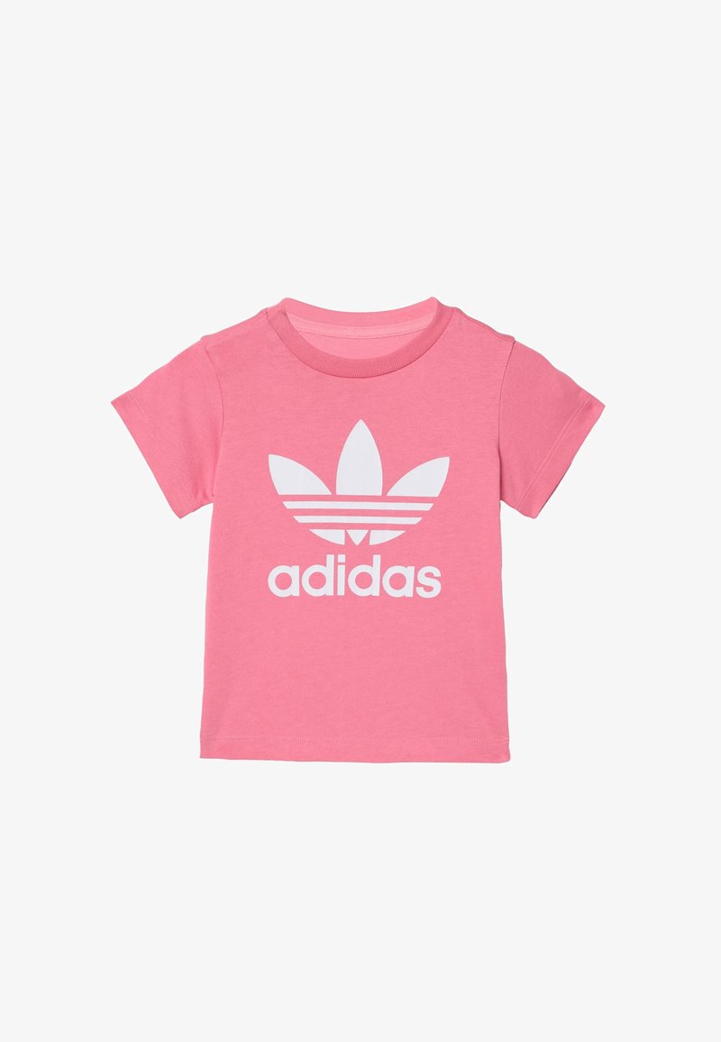 Różowa bawełniana koszulka z krótkim rękawem, z dużym białym logo Adidas i trzema białymi paskami u góry. Klasyczny okrągły dekolt.