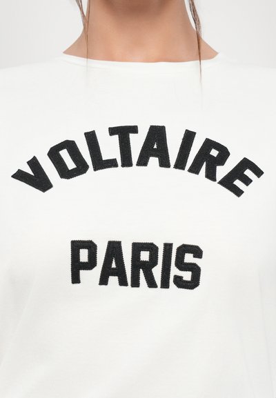 Weißes Baumwoll-T-Shirt mit fettem, schwarzem, gesticktem Text "VOLTAIRE PARIS", der mittig auf der Brust in einer stilisierten Schriftart platziert ist. Rundhals-Ausschnitt ist sichtbar.