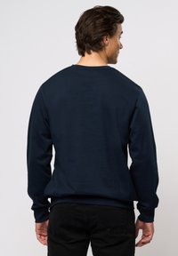 Marinblå sweatshirt med lange ermer, rund hals og en glatt tekstur. Baksiden har et enkelt design uten synlige logoer eller mønstre.