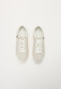 Sneakers grigio chiaro con lacci bianchi e dettaglio con zip. Realizzate in materiale morbido, con punta arrotondata e superficie testurizzata. Design minimalista.