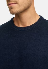 Navyblauwe gebreide trui met een ronde ribbelhals, met een zachte textuur en een close-up van het kraaggebied.