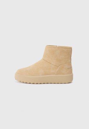 Botín beige de ante con suela gruesa, puntera redondeada y plataforma plana, diseñado para un uso casual.