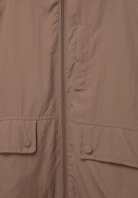 Brown insulated jacket featuring a front zipper, stitched texture, two buttoned flap pockets, and a smooth fabric finish.
