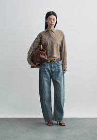 Brown and white striped button-up shirt, high-waisted baggy blue jeans, brown belt, and brown leather handbag. Simple heeled sandals.
