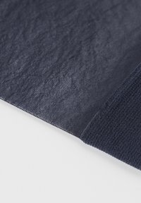 Tejido azul marino con una superficie texturizada, que presenta una sección lisa y otra acanalada, dispuesto sobre un fondo blanco.