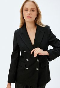 Zwarte gestreepte dubbelgeknoopte blazer met zilveren knoopaccenten, geknipte revers en een op maat gemaakte pasvorm met een gladde textuur.