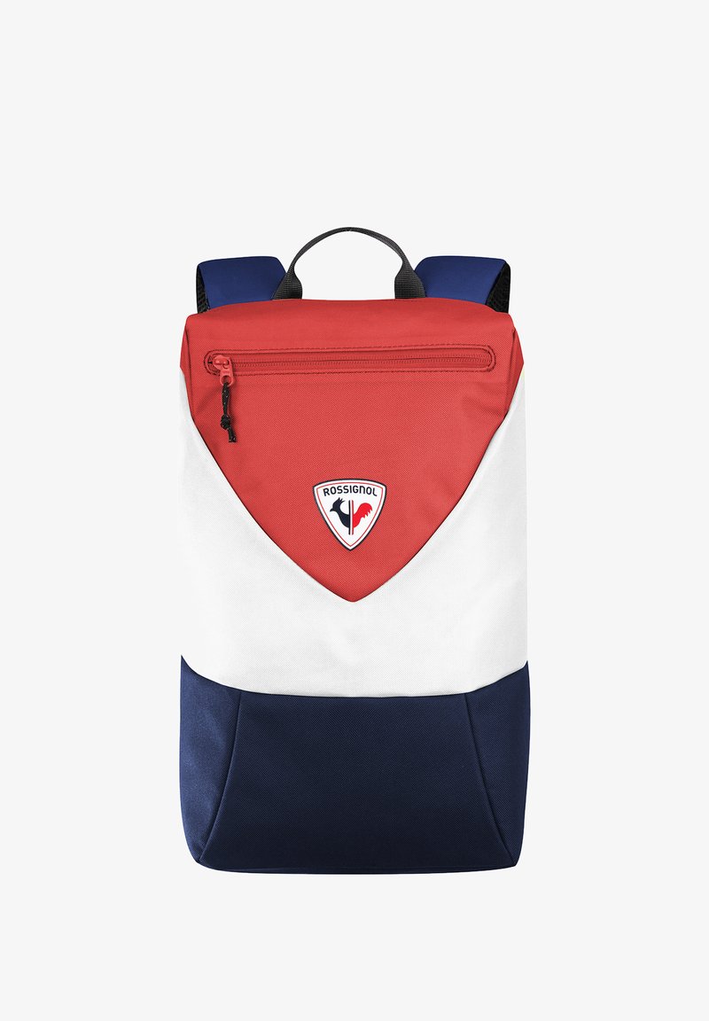 Röd, vit och marinblå ryggsäck med en triangulär design, som har en framficka med dragkedja och Rossignol-logotyp på framsidan. Hållbart tyg, justerbara remmar.