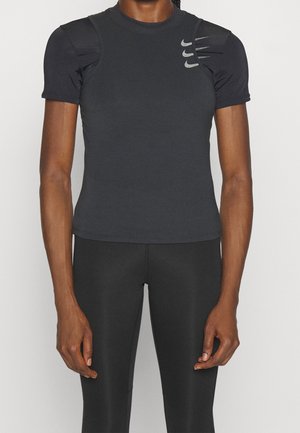 T-shirt de sport gris foncé à manches courtes, avec des accents texturés sur les épaules et le logo Nike imprimé sur la poitrine. Matière lisse et ajustée.